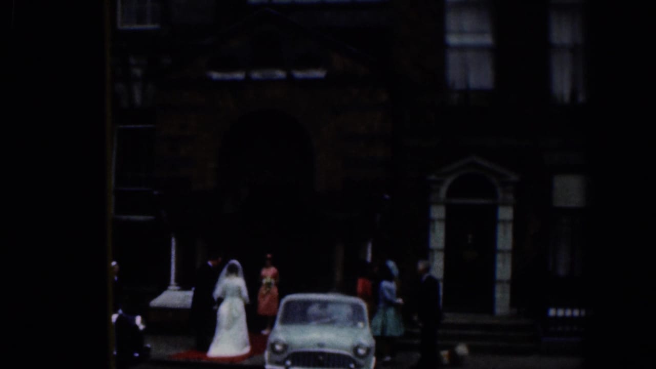 1961 Dublin church exterior with a bride in a white gown, wedding guests, and a small period car near the entrance.
