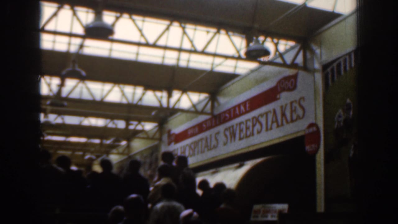 Dublin 1961 interior frame showing waiting figures, overhead glass, steel trusses, and sweepstakes signage.