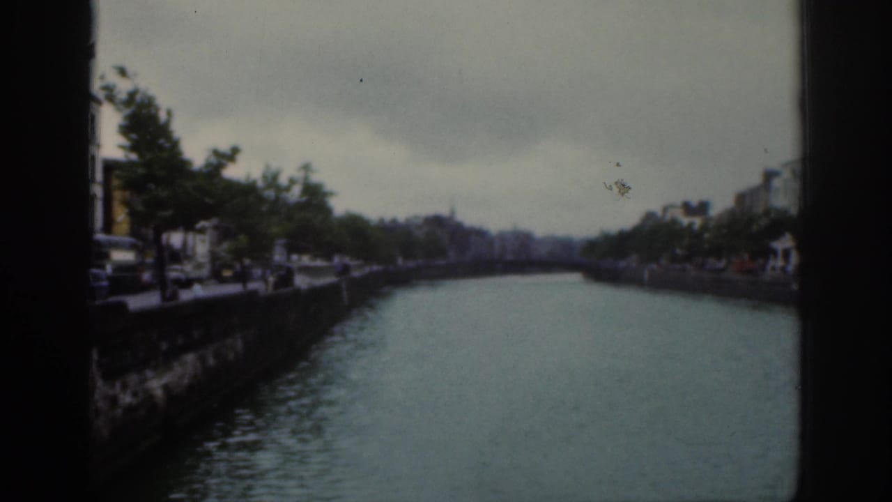 River or canal view from a bridge with buildings and trees under an overcast sky.