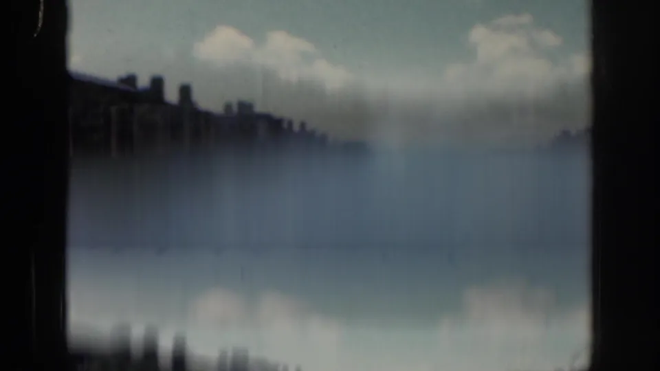 A soft final 1961 Dublin frame appears to show a riverside or bridge view, with dark building silhouettes, pale water, clouds, and strong film blur.