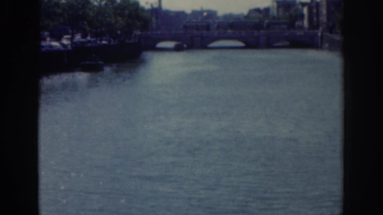Dublin river and stone bridge view from 1961 home-movie footage, framed by dark 8mm contact-sheet edges.