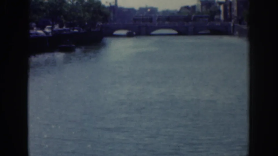 Dublin river and stone bridge view from 1961 home-movie footage, framed by dark 8mm contact-sheet edges.