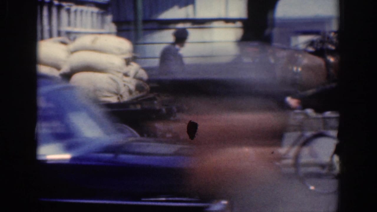 Dublin street traffic with cart sacks, driver, cyclist, and a blurred passing car in 1961 8mm footage.
