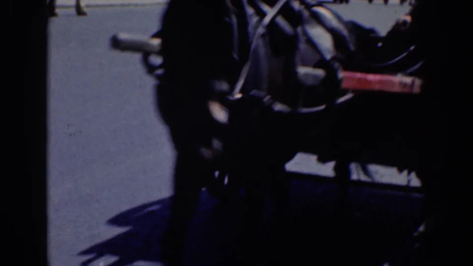 Dark 8mm frame of a horse-drawn carriage on a Dublin street, with pavement and distant pedestrians visible.