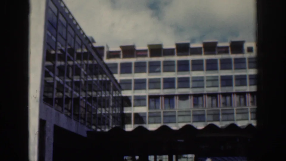Angled 1961 Dublin view of a modern multi-story building, showing a side facade, window grid, awnings, and cloudy sky.