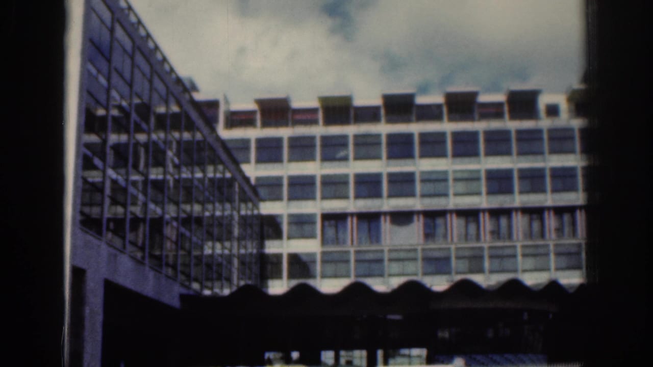 1961 Dublin home-movie frame showing a modern grid-window building with a darker glass-sided structure at left.