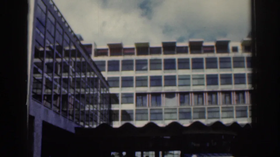 1961 Dublin frame looking up toward a modernist office-like building with repeated windows and deep shadow below.