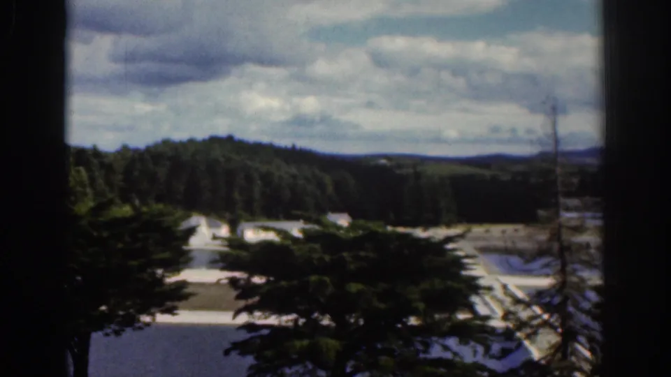 1961 Dublin countryside view with trees in the foreground and water treatment basins visible below distant wooded hills.