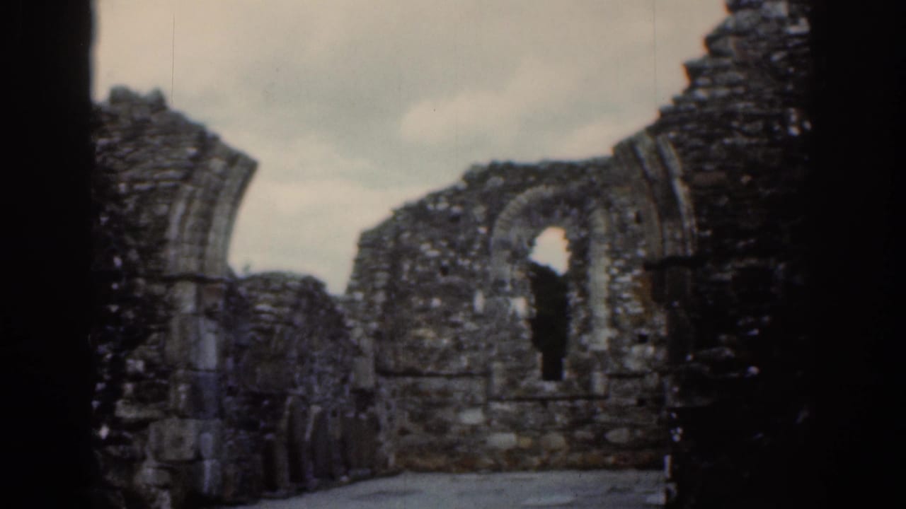 Arched stone openings and broken walls stand under a cloudy sky.