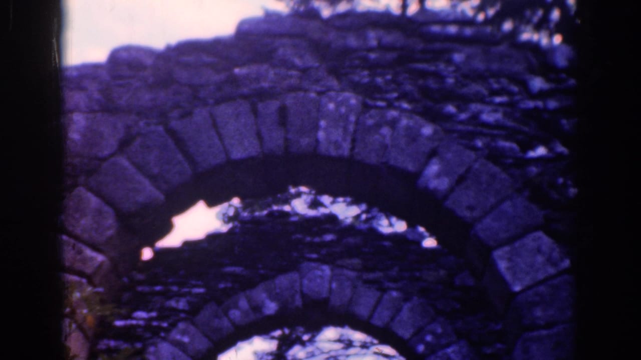 Close view of weathered stone arches with trees behind them.