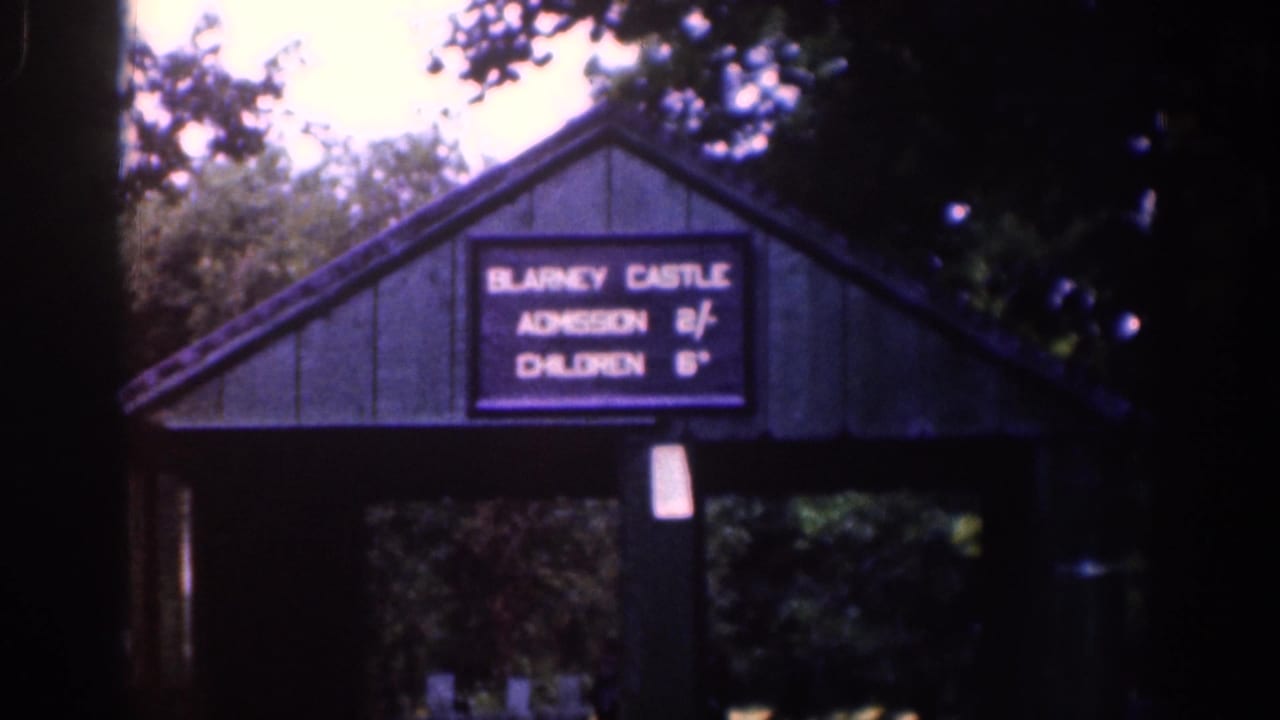 1961 Ireland travel frame showing a Blarney Castle admission sign on a small entrance structure under trees.