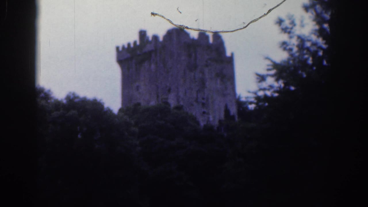 Distant view of Blarney Castle tower in 1961 8mm footage, with foliage at the sides, pale sky, and visible film wear.