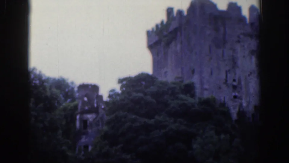 1961 Dublin frame with a large castle tower at right and a smaller turret-like structure amid trees beneath a cloudy sky.