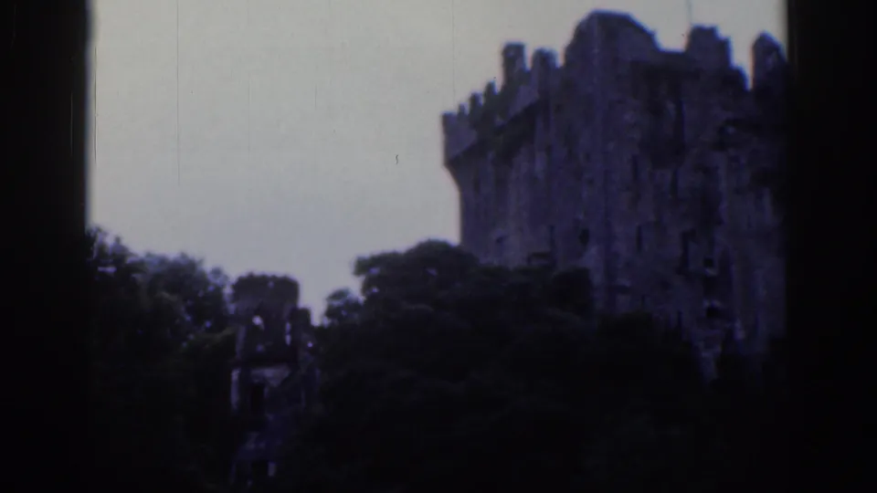 1961 Dublin 8mm frame showing a weathered castle tower near the right edge, partly screened by dark foliage.