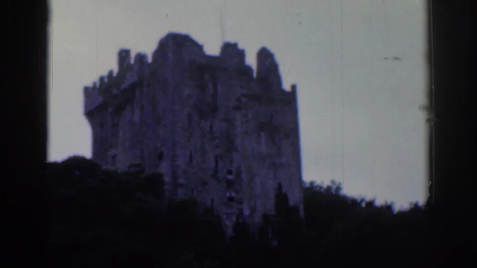 1961 Dublin 8mm frame showing a large crenellated stone ruin partly obscured by trees against a pale sky.