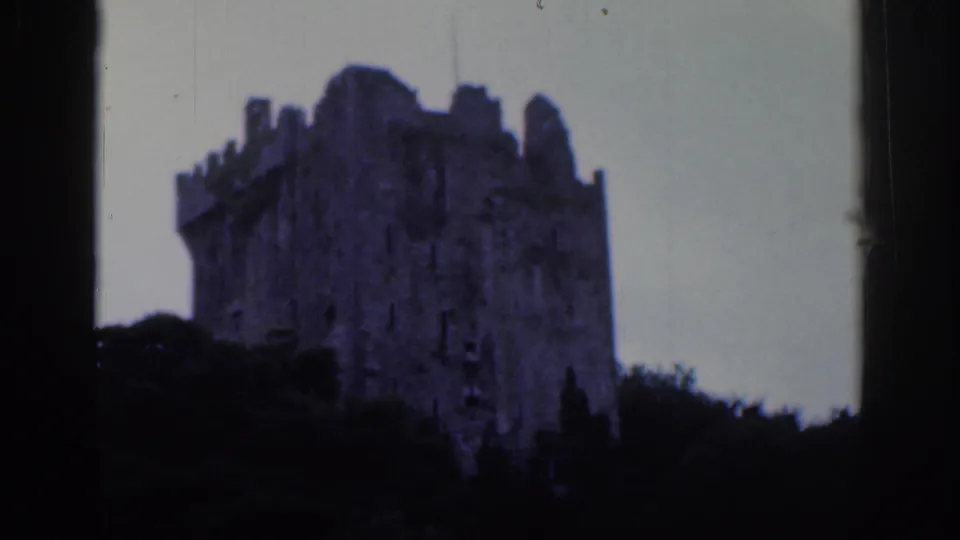 1961 Dublin 8mm frame with a crenellated stone ruin silhouetted by trees and visible scan borders.