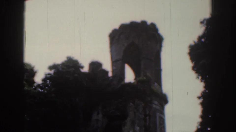 1961 Dublin 8mm frame showing a smaller ruined turret with an arched opening, ivy and surrounding trees.
