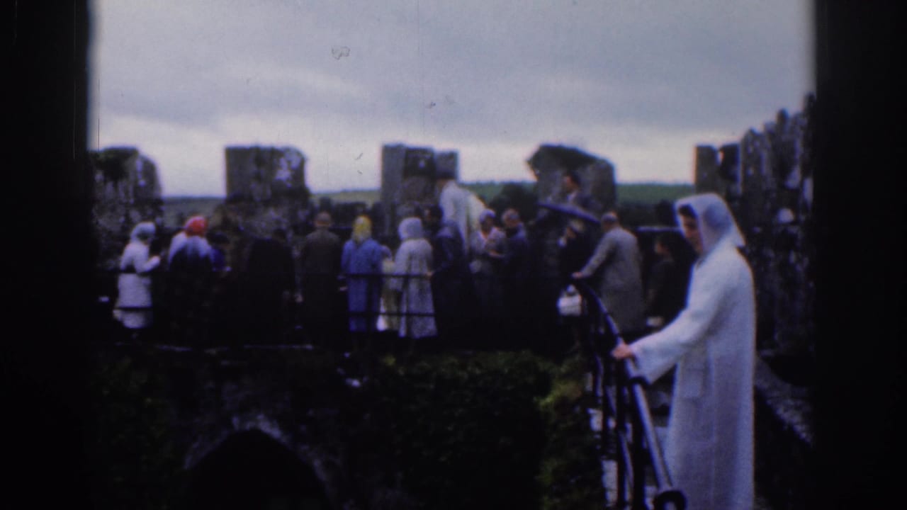 Tourists in raincoats and hats stand on old castle battlements in Dublin, Ireland, in 1961 home-movie footage.
