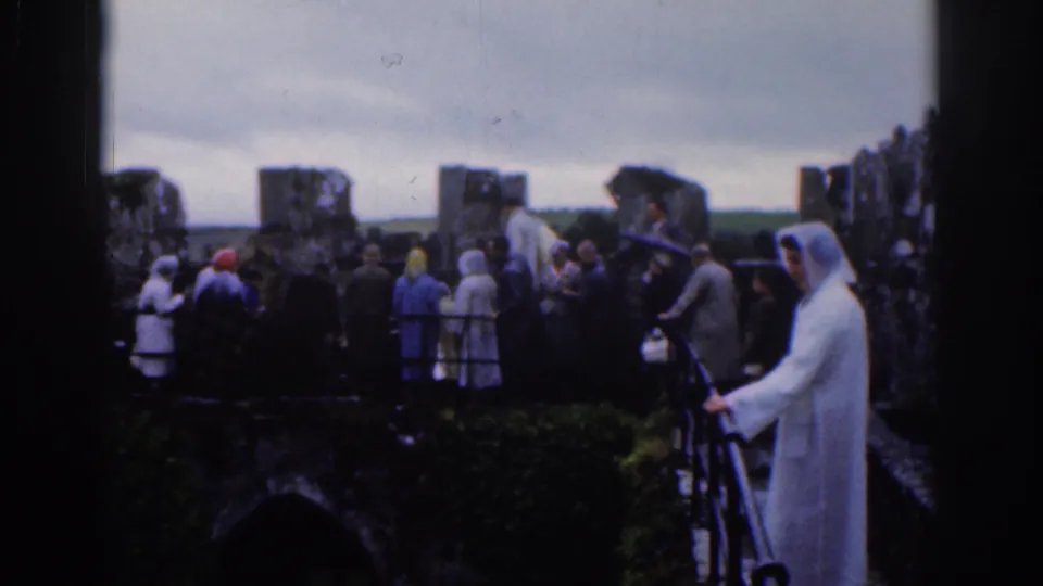 Tourists in raincoats and hats stand on old castle battlements in Dublin, Ireland, in 1961 home-movie footage.