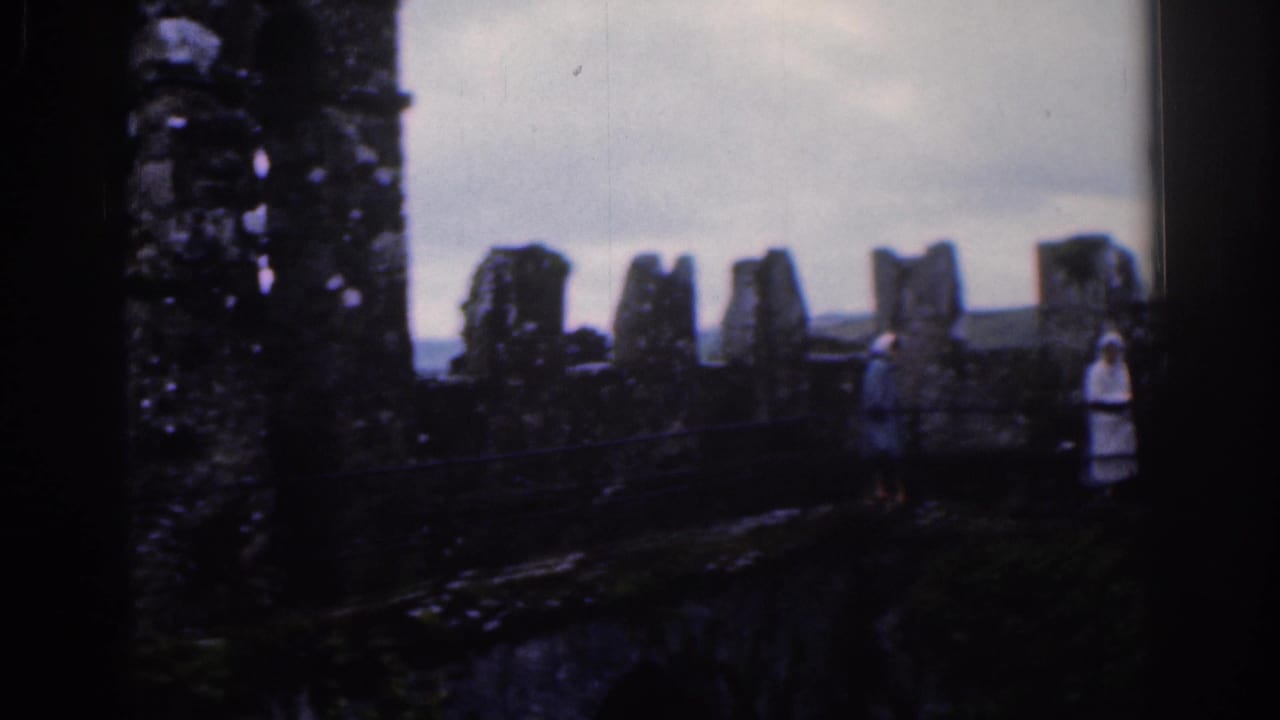 Weathered battlements at an old Dublin castle frame a lone visitor near the wall in muted 1961 8mm footage.
