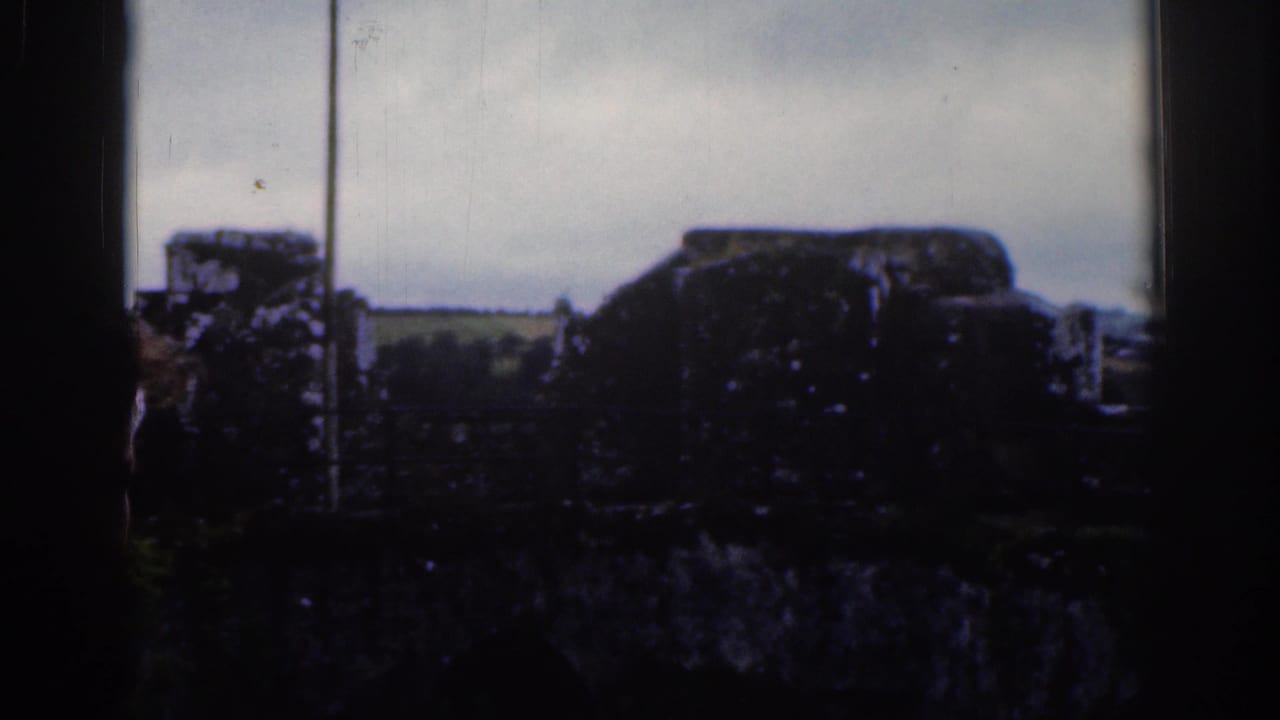 Dark-framed view of stonework, sky, and distant open land.