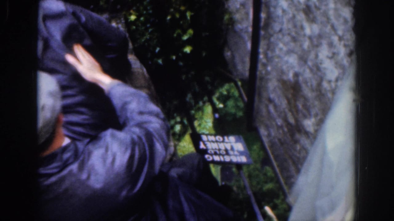 The home-movie frame shows a man reaching into the ditch-like area, with a small Blessing Stone sign partly visible below.