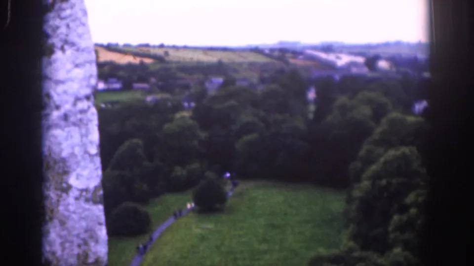 1961 Dublin home-movie still with stonework in the foreground and a soft view over trees, parkland, fields, and buildings.