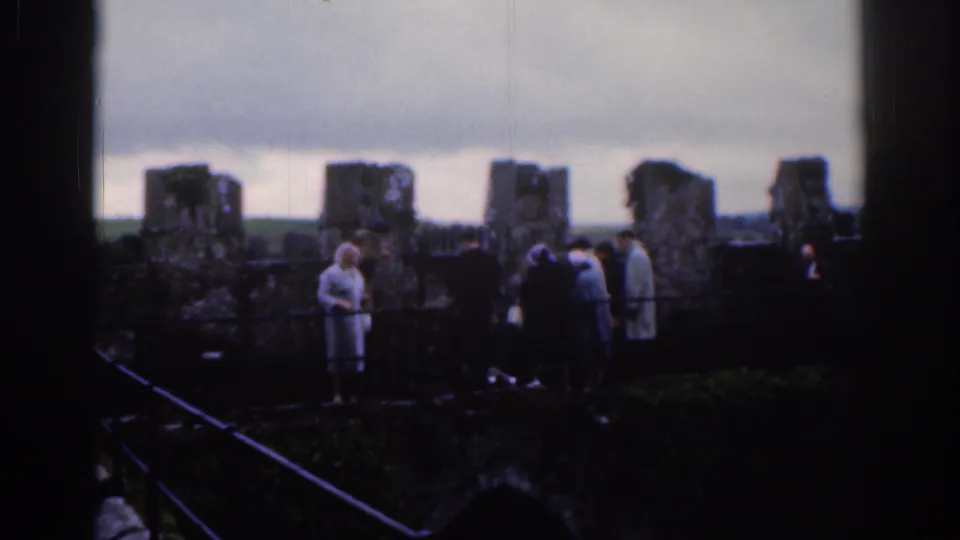 Home-movie view of tourists at old stone ruins in Dublin, with steps and railings visible in the foreground.