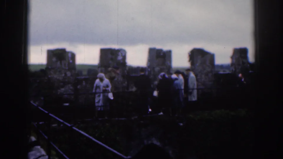 1961 Dublin home-movie frame showing tourists in coats gathered among weathered stone fortress walls.