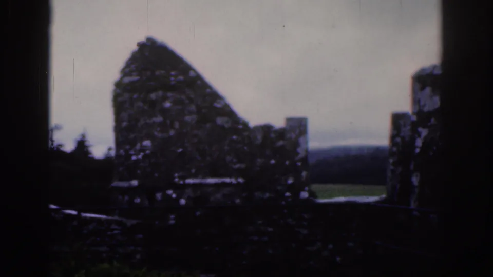 Handheld 1961 Dublin home-movie view of a ruined stone wall, battlements, railings, and countryside beyond.