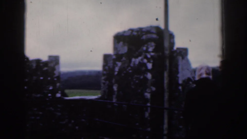 1961 Dublin 8mm frame of weathered battlements and stonework with a visitor partly visible near the edge.