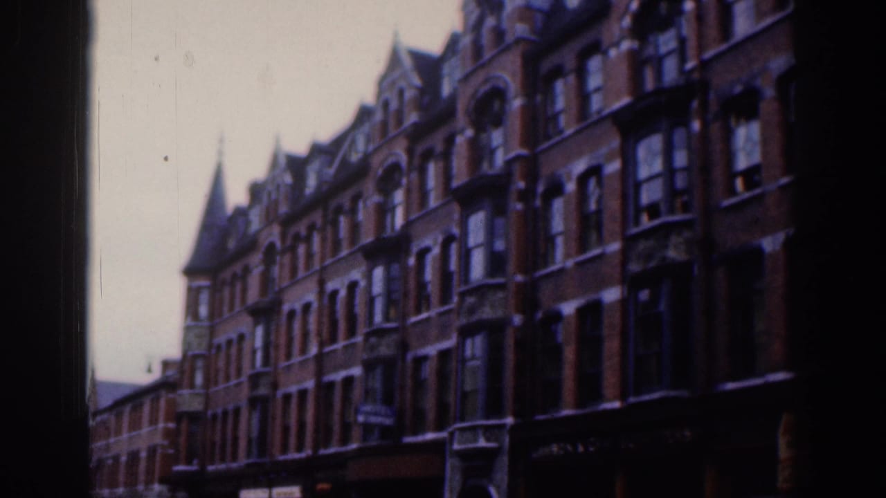 Row of ornate brick buildings with bay windows and dark border at the side.