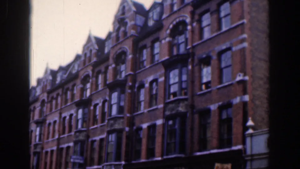 1961 Dublin 8mm frame with a closer look at red-brick townhouse fronts, bay windows, arched upper windows, and soft film grain.