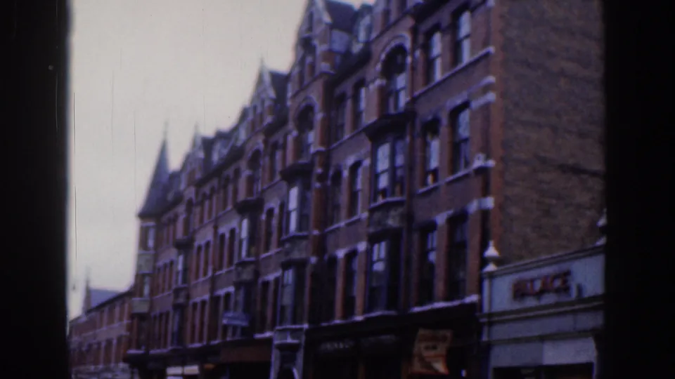 1961 Dublin view of tall red brick facades, bay windows, ground-floor shops, and visible PALACE signage on the right.