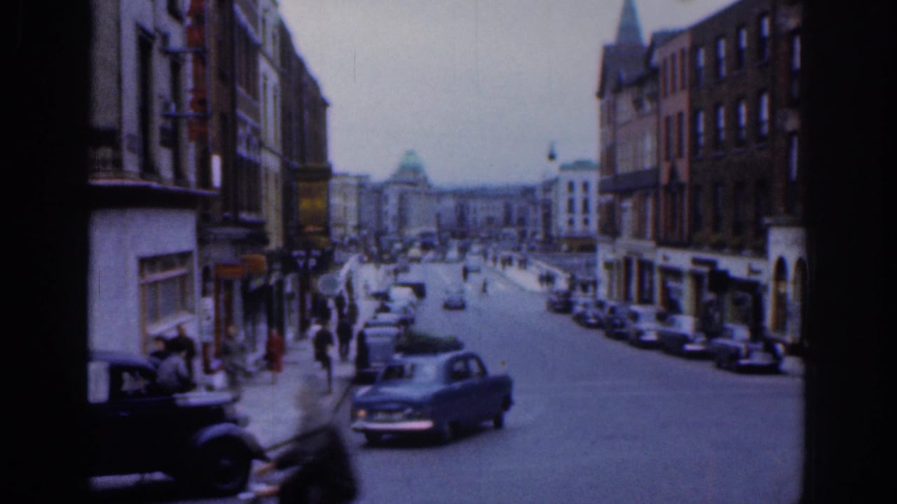 1961 Dublin street view with mid-century cars moving past pedestrians, storefronts, brick facades, and a distant domed building.