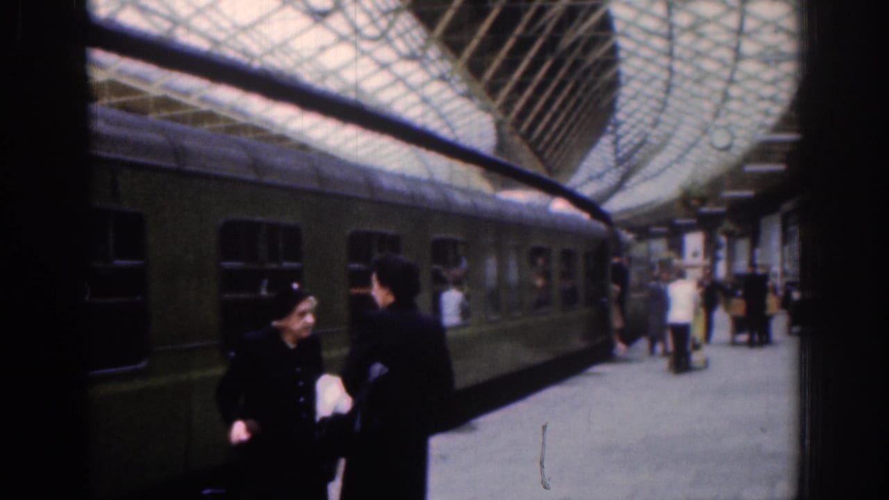 1961 Dublin station platform with a green passenger train, people in coats and hats, and an arched glass roof overhead.