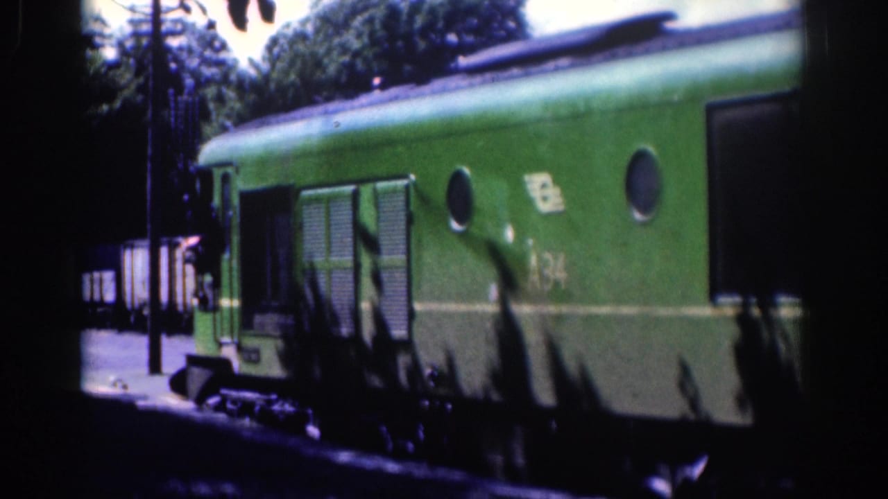 1961 Dublin 8mm frame showing a green railway carriage at a platform, with trees, a utility pole, and soft daylight exposure.