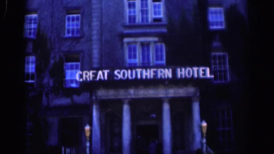 Night 8mm view of the Great Southern Hotel facade in Dublin, with white illuminated lettering, windows, and entrance columns.