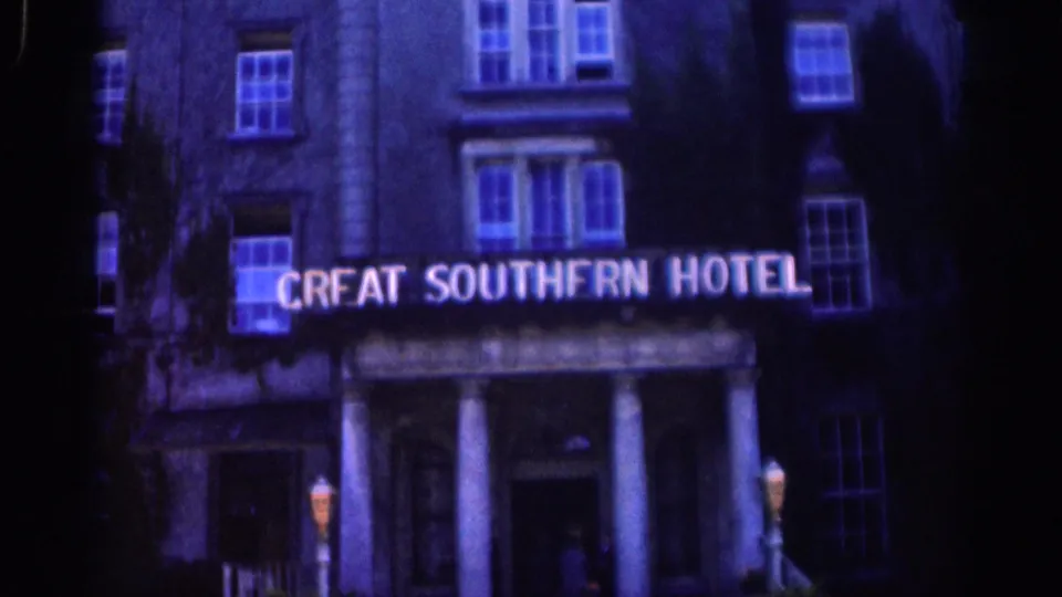 Great Southern Hotel facade in Dublin, with the sign lit above a columned entrance and upper windows visible in dark exposure.