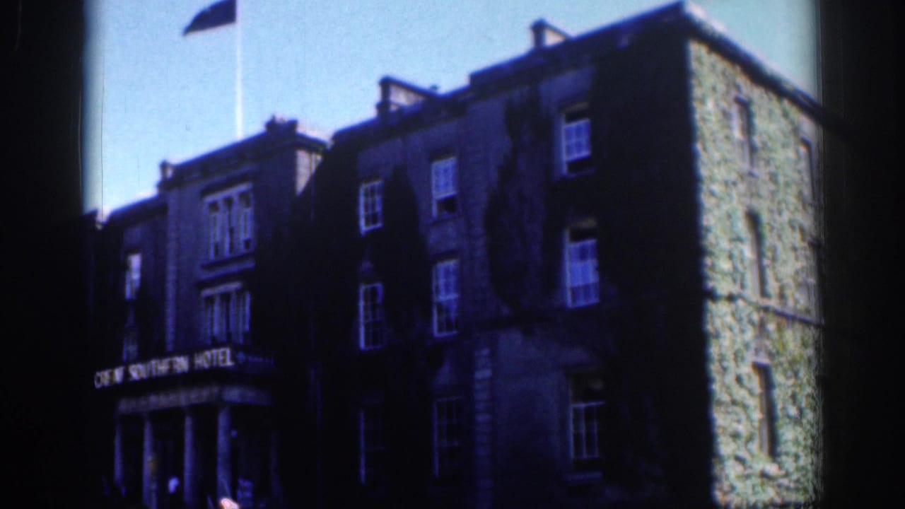 1961 Dublin 8mm frame showing a stone hotel facade with signage, upper windows, and a flag above the roofline.