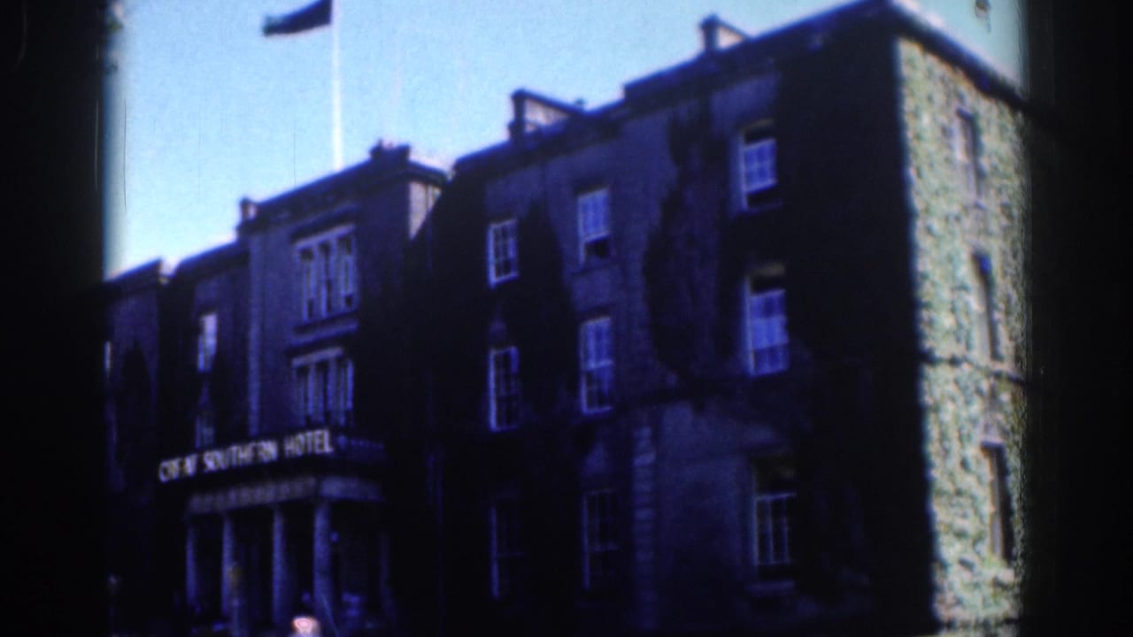 Stone hotel facade with sign, windows, and flag in strong contrast.
