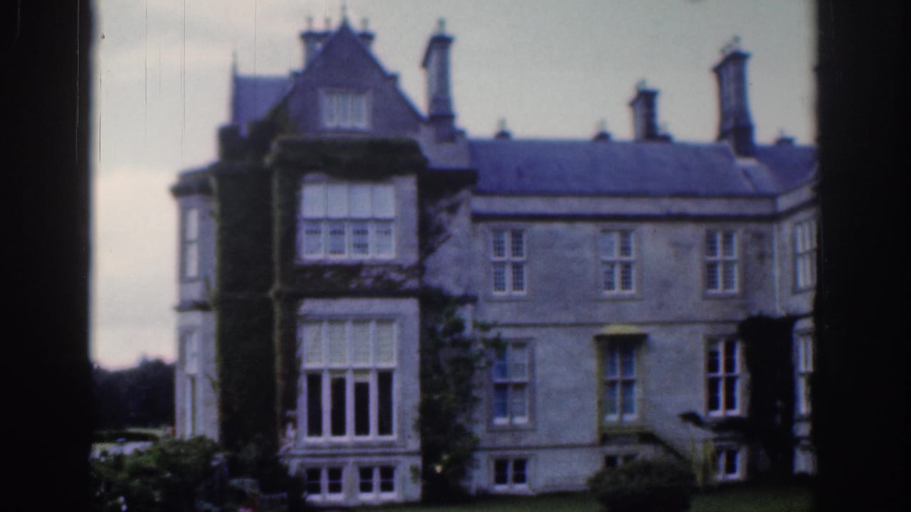 1961 Dublin home-movie frame showing a large stone manor estate with ivy, chimneys, tall windows, and a lawn.