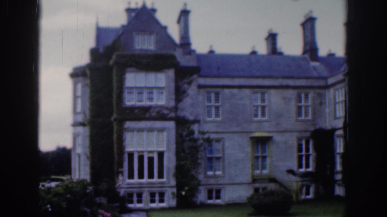 Stone estate facade with ivy, chimneys, large windows, lawn, and dark frame edge.