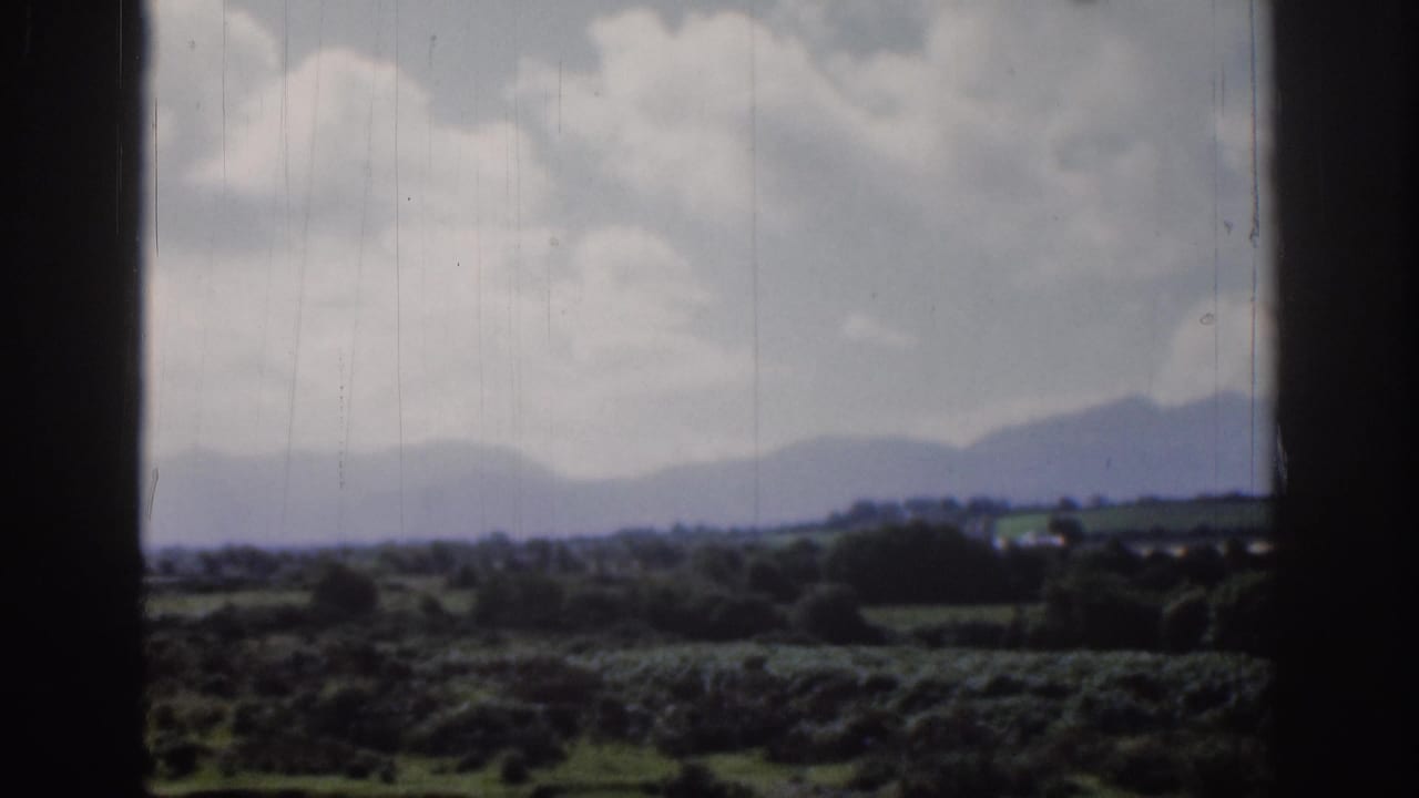 Rural fields and low hills sit beneath a bright sky with layered clouds.