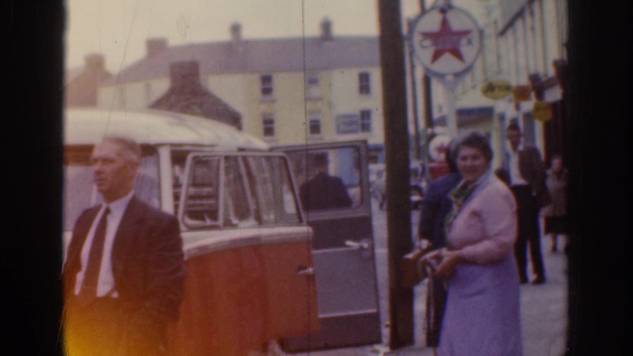 1961 Dublin street view with a suited man, a woman in a light dress, pedestrians, and a two-tone van with its side door open.