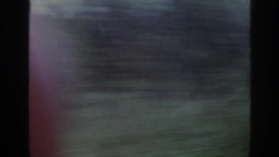 Train-window view in Ireland, 1961, with green field, distant horizon, and strong motion blur from travel.