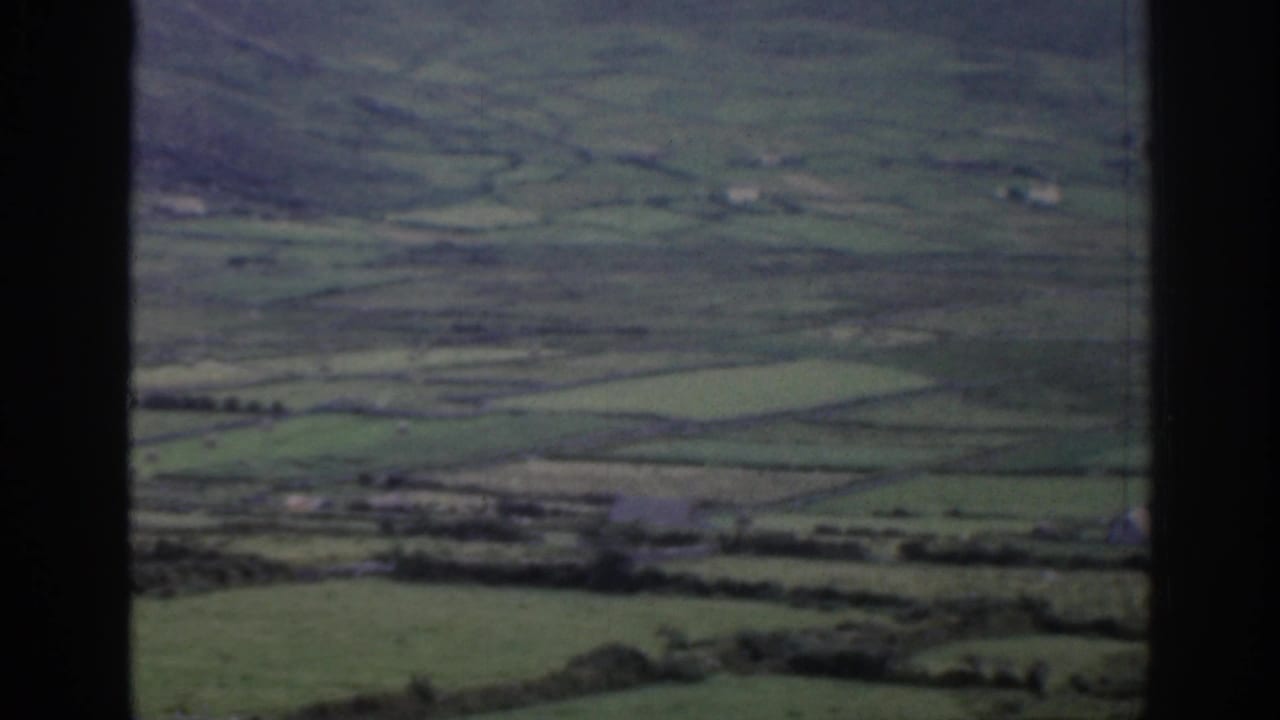 Wide rural valley with green fields, low hills, and dark vertical border through the center.