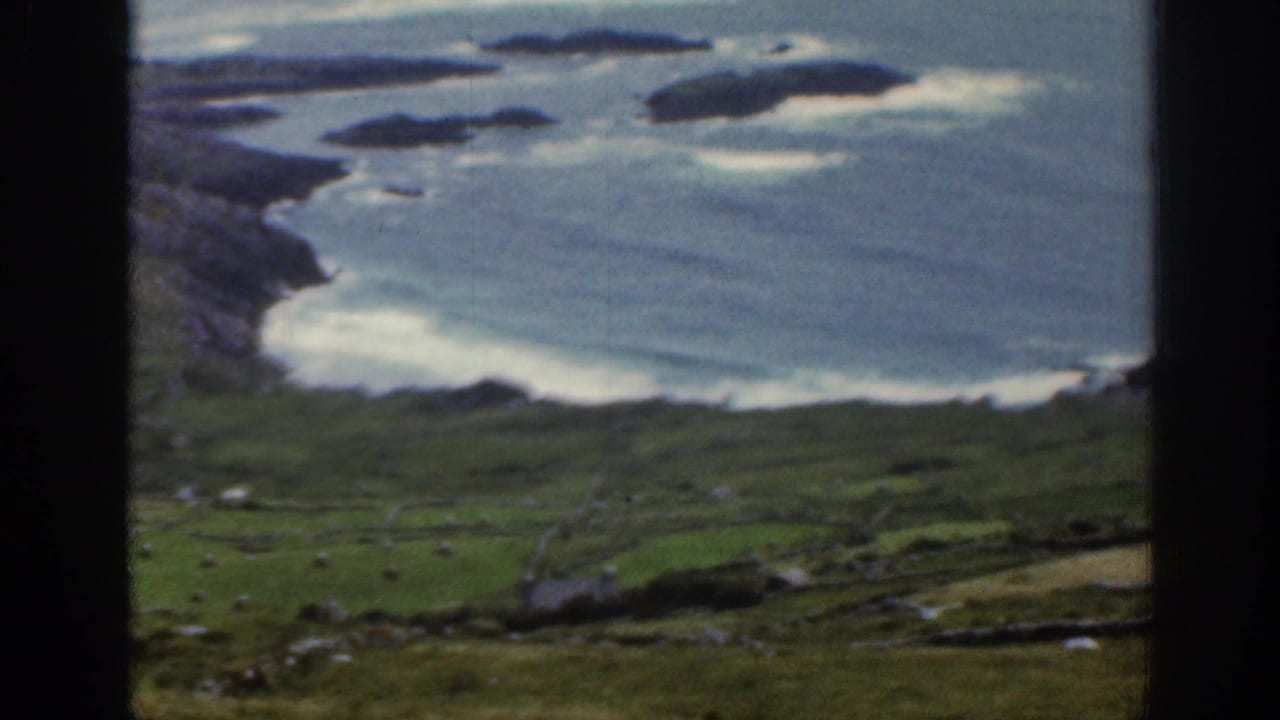 Rocky coast and blue bay with small offshore islands, viewed through dark vertical framing.