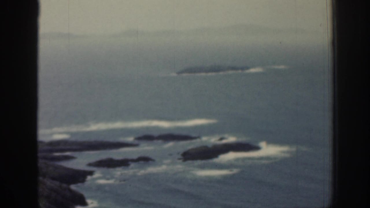 Rocky shoreline and small islands beyond a vertical window divider.