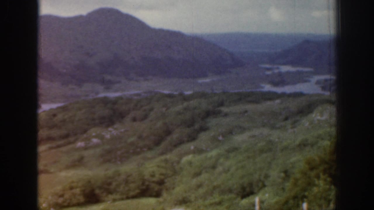 Faded 8mm view from Ireland in 1961 showing hillside vegetation, distant mountains and water below.
